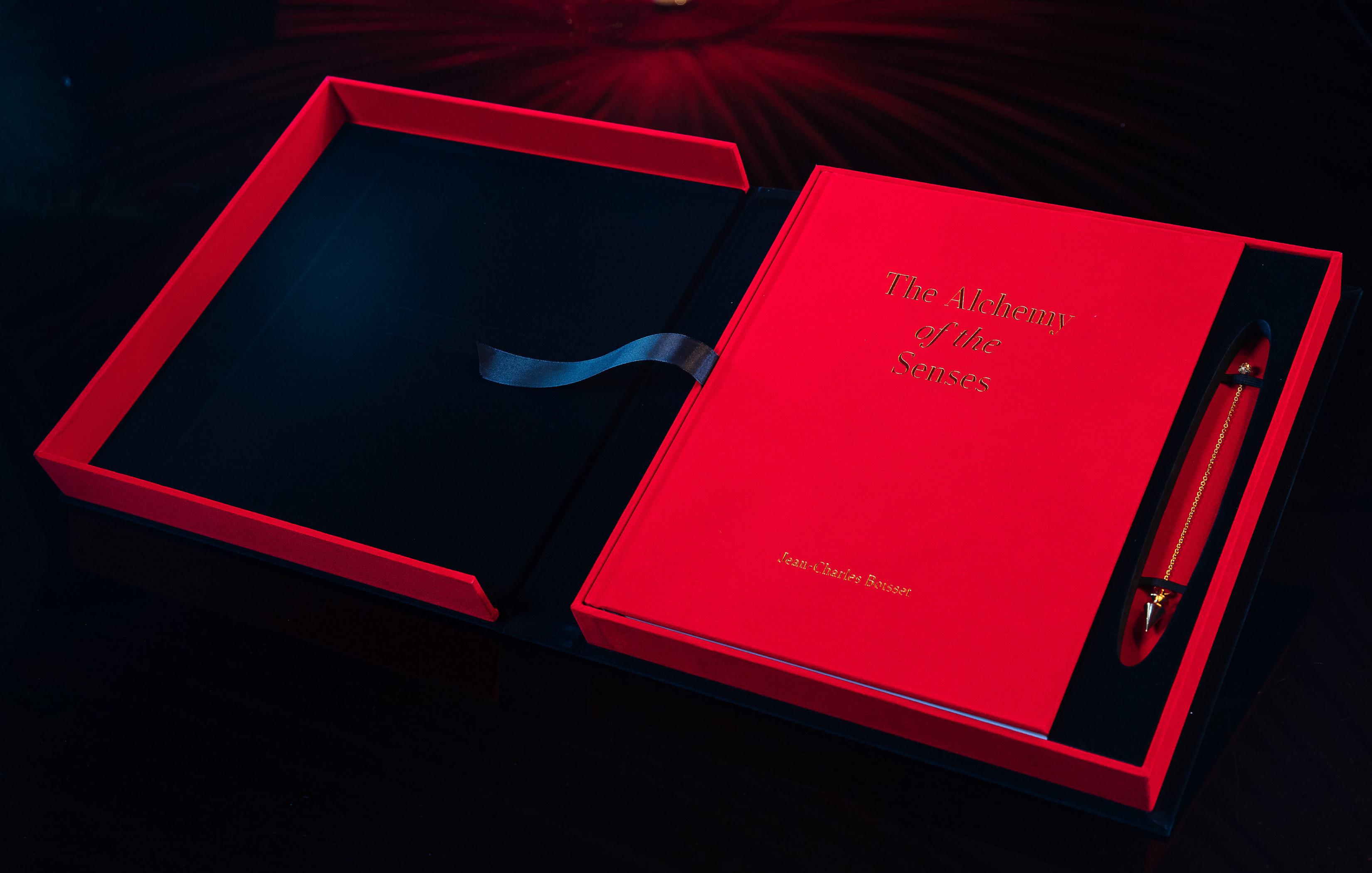 JCB's book, Alchemy of the Senses, in a red box, red cover, jewelry on the side